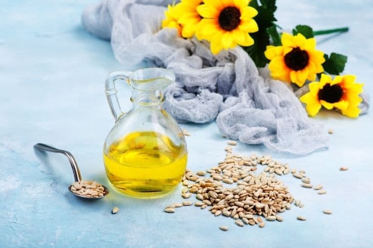 Aceite de girasol en jarra con semillas de girasol a su lado.