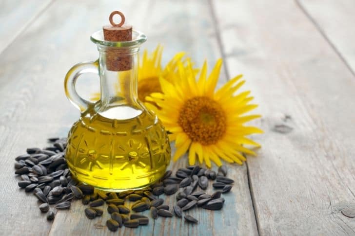Aceite de girasol en jarra con semillas de girasol a su lado.